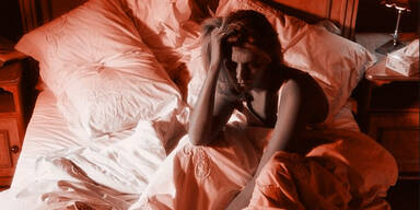 Frau sitzt schlaflos im Bett